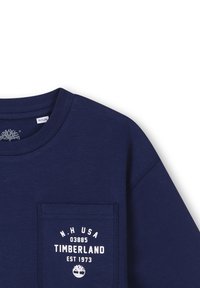 Donkerblauwe katoenen longsleeve shirt met een borstzak met wit Timberland-logo en oprichtingsdatum, ronde halslijn en een gestructureerde stof.