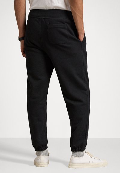 Schwarze Jogginghosen aus weichem Material, mit einer lockeren Passform, elastischen Bündchen, einer Gesäßtasche und Seitennähten.