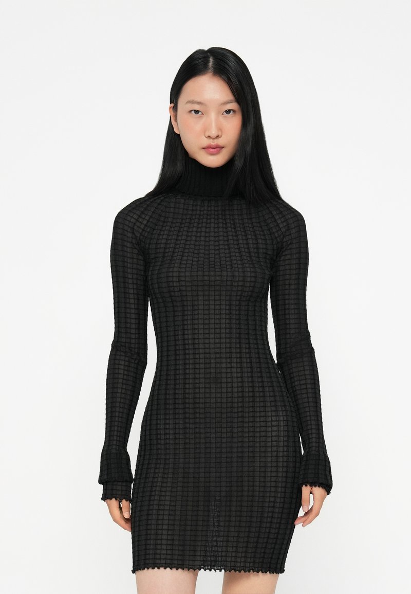 Μαύρο φόρεμα με μακριά μανίκια, εφαρμοστή σιλουέτα, υφασμάτινο σχέδιο καρό, υψηλό λαιμό και λεπτομέρεια με κυματιστό τελείωμα.