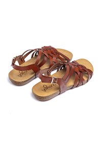 Sandalias de cuero marrón con un diseño trenzado, correa de tobillo ajustable y suela acolchada con un logotipo estampado en una plantilla beige.