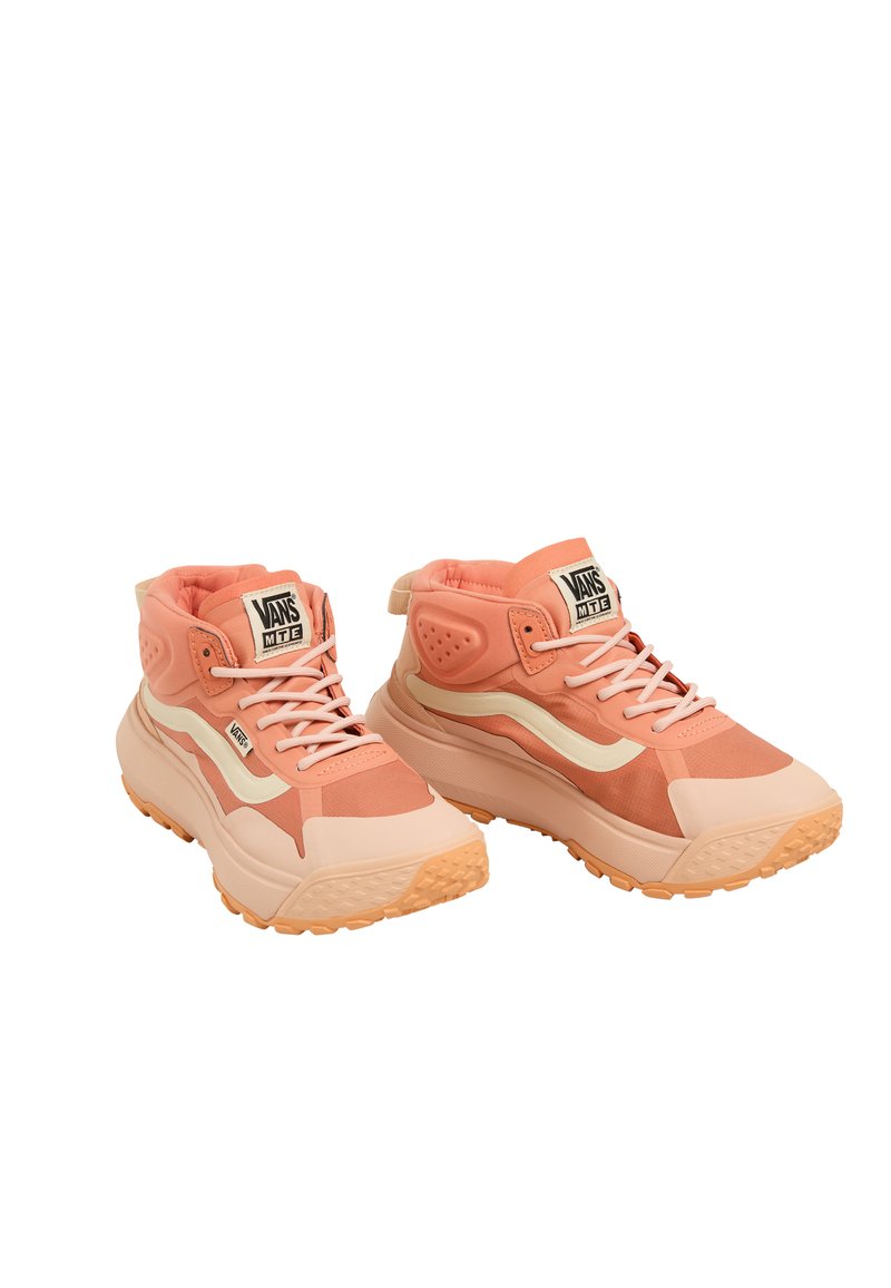 Zapatillas altas en color melocotón claro y crema, con una parte superior de tela texturizada, suela de goma y el logo de Vans en la lengüeta.