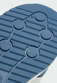 Sole tenisky s textúrovaným modrým gumovým povrchom, ktorý má kruhové akcenty a vystúpené línie pre lepšiu priľnavosť.