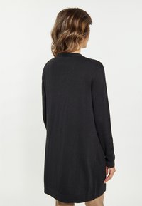 Zwarte lange mouwen gebreide cardigan met een rechte snit, geribbelde manchetten en een afgeronde zoom. Kenmerkend is de gladde textuur en een achteraanzicht.