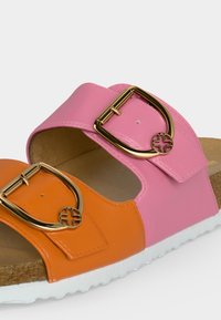 Πέδιλο με ανοικτά δάχτυλα και ροζ και πορτοκαλί λουριά από δέρμα, το καθένα με χρυσή πόρπη με διακοσμητική λεπτομέρεια σε σχήμα σταυρού.