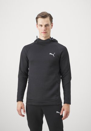 Sudadera con capucha negra de diseño ajustado, fabricada con un tejido suave. Presenta un sutil logo de Puma en gris, bolsillos frontales con cremallera y mangas texturizadas.