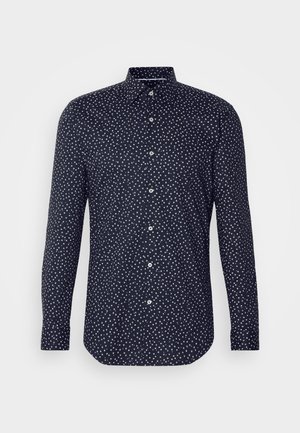 Navy shirt with a button-down collar, featuring a scattered white dot pattern. Long sleeves with button closures and a curved hem.