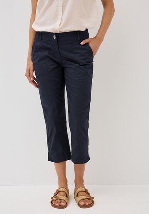 Pantaloni cropped blu navy realizzati in tessuto testurizzato, con vita elastica, due tasche laterali e chiusura con bottone frontale. Abbinati a sandali beige.