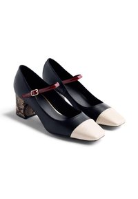 Black Mary Jane block heels with white textured toe caps, red patent strap, and snakeskin-patterned heels on a white background.