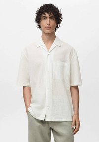 Korte mouw shirt in lichte, gestructureerde stof; witte kleur met subtiele strepen, knoopsluiting aan de voorkant en één borstzak.