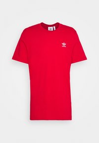 Červené bavlněné tričko s kulatým výstřihem, krátkými rukávy a malým bílým logem Adidas na levé části hrudi. Jednoduchý design, bez vzorů.