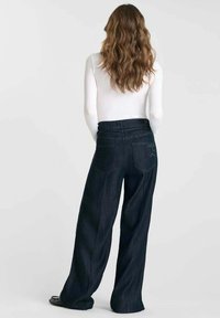 Zwarte ruime denimpantalon met hoge taille, voorzien van twee achterzakken en subtiele stiksels. Het materiaal heeft een gladde textuur.