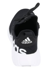 Zapatilla deportiva negra con parte superior de malla texturizada, logo blanco y suela blanca de contraste. Cuenta con un tirador y cordones negros.