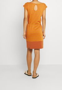 Oranssi raidallinen mekko, jossa on lyhyet hihansuut, avainreikätakaosa ja tiukka vyötärö. Tekstuurin näyttää olevan pehmeä ja helma on liukuvärjätty.