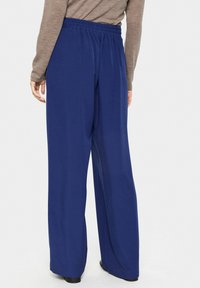 Marineblauwe wijde broek met een elastische tailleband, gemaakt van een soepele, lichte stof. Het ontwerp is losvallend met een rechte snit.