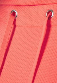 Tessuto di un vivace rosa brillante con una texture caratterizzata da un motivo intrecciato, con lacci a contrasto passati attraverso occhielli metallici per la chiusura.