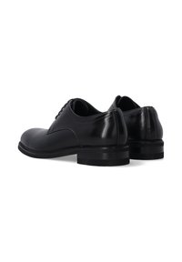 Schwarze lackierte Leder-Herrenschuhe mit flachen Absätzen und Schnürdesign, von hinten auf einem weißen Hintergrund gezeigt.