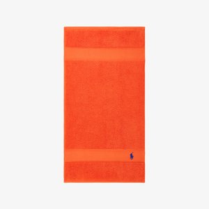 Πορτοκαλί πετσέτα μπάνιου με υφή στην επιφάνεια, που διαθέτει μια λεία λωρίδα στο πάνω και κάτω μέρος· περιλαμβάνει ένα μικρό μπλε λογότυπο στην κάτω γωνία.
