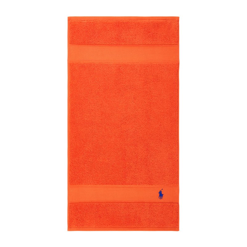 Πορτοκαλί πετσέτα μπάνιου με υφή στην επιφάνεια, που διαθέτει μια λεία λωρίδα στο πάνω και κάτω μέρος· περιλαμβάνει ένα μικρό μπλε λογότυπο στην κάτω γωνία.