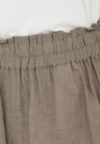 Gonna di lino in un colore marrone tenue con una cintura elastica arricciata e una consistenza morbida, caratterizzata da sottili motivi verticali.