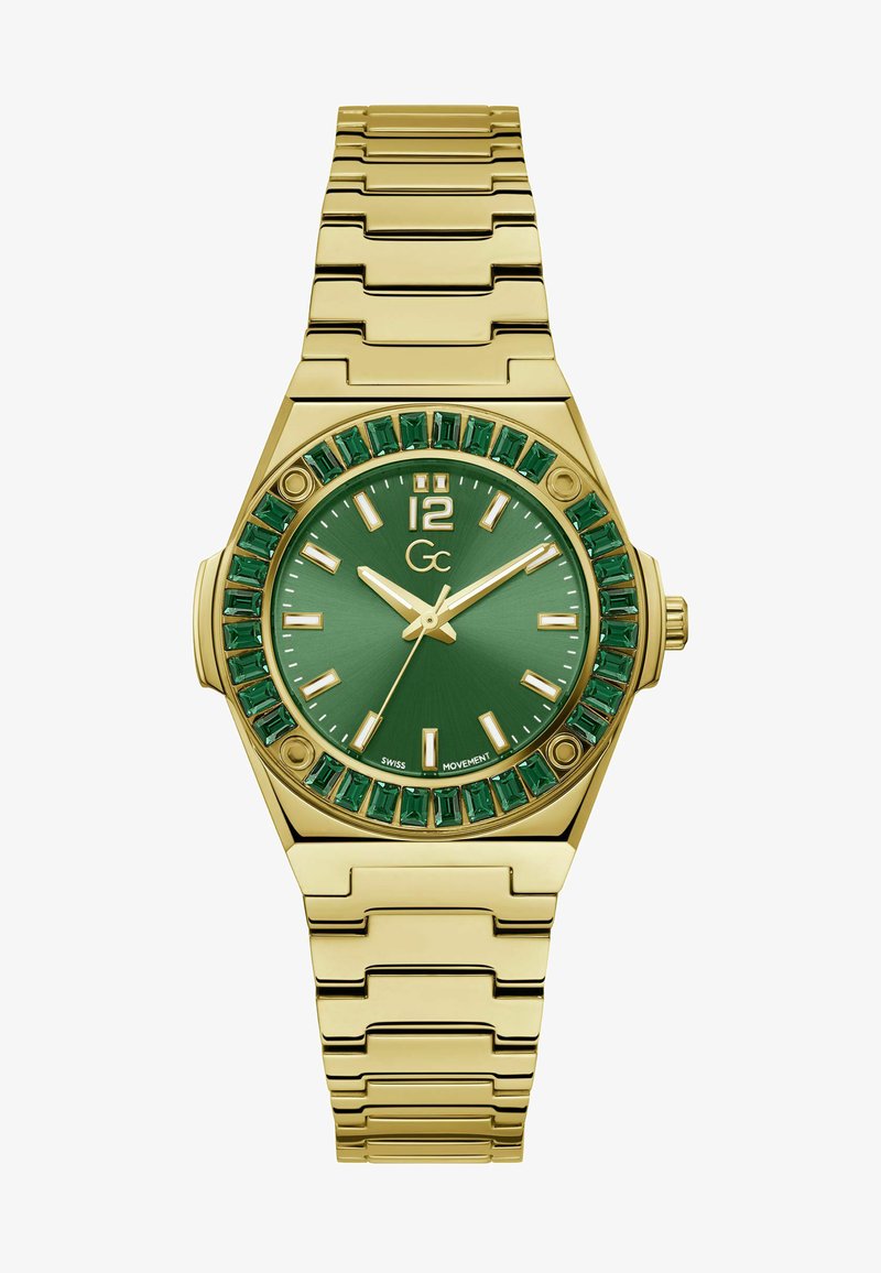 Guldfärgad armbandsur med en grön urtavla, smaragdslipade detaljer runt boettens kant och ett metallarmband. Har vita timmarkörer.