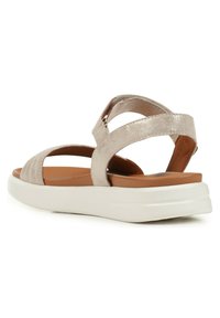 Sandal in oro rosa metallico con più cinturini, soletta imbottita e suola piatta bianca. Presenta una parte superiore testurizzata con dettagli di cucitura.