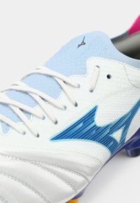 White football boot with blue accents, textured synthetic upper, lace-up design, and purple outsole. Features a distinctive logo on the tongue.