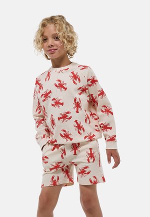 Ensemble de détente en coton avec une base crème et un motif de homard rouge. Le haut a des manches longues et le short est de longueur genou.