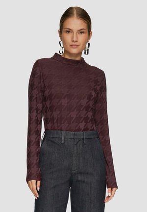 Langsleeve, hoge hals top in donker bordeaux met houndstooth patroon, gecombineerd met donkere hoge taille broeken. Glad stoftextuur.