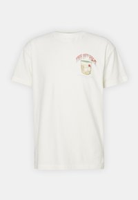 Vit bomull t-shirt med korta ärmar, med en färgglad grafik av en drink med körsbär och texten "DEN 10:E H ÅLET."