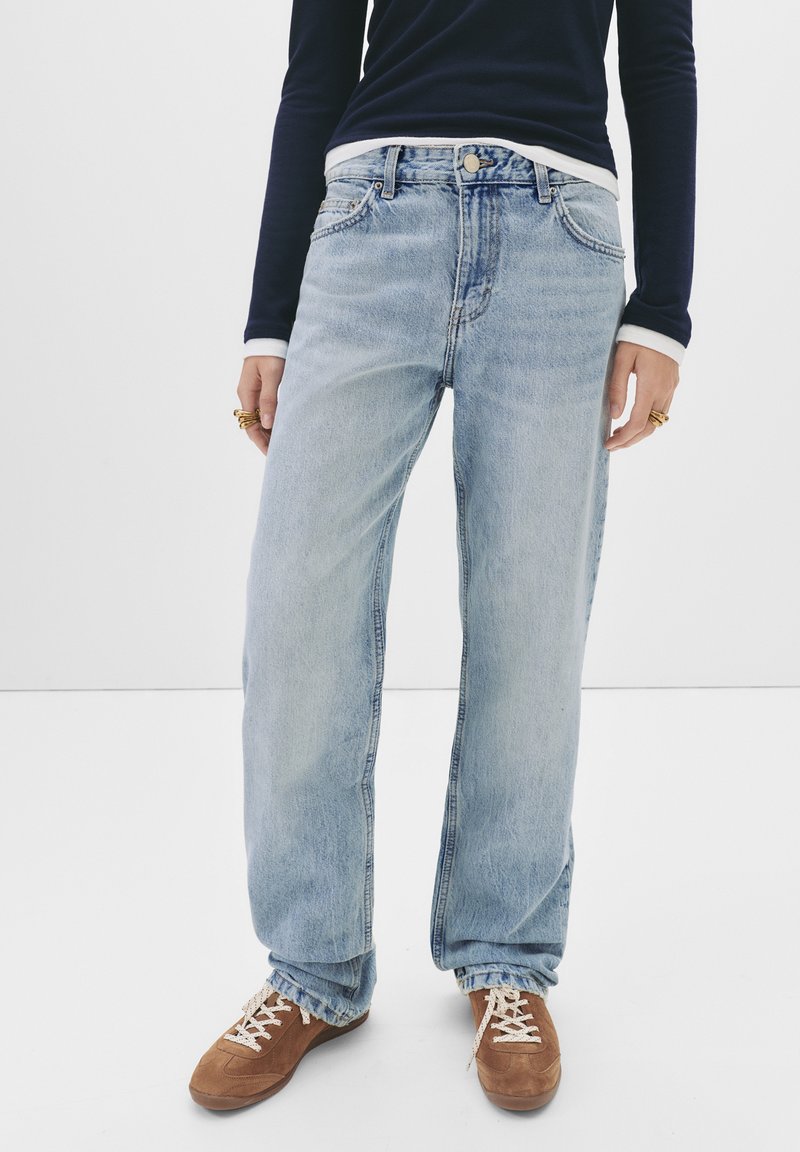 Ljusblå, vida jeans i denim med en blekt tvätt. Har en traditionell femficksdesign och fransad kant. Kombineras med bruna skor.