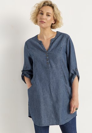 Denim tuniek in medium blauw, met een V-hals, vier knopen, driekwart opgerolde mouwen en zijzakken. Zacht, lichtgewicht stof.