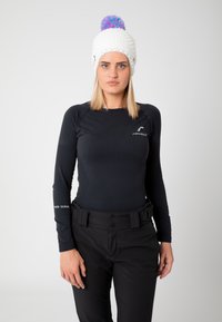 Black long-sleeve base layer top with textured design, paired with black pants featuring a belt. White knitted beanie with colorful pom-pom.