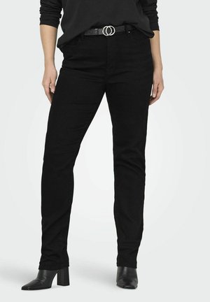 Jeans en denim noir avec une coupe slim et des détails minimalistes, associés à une ceinture noire avec double boucles circulaires en argent et des bottes à talons hauts.