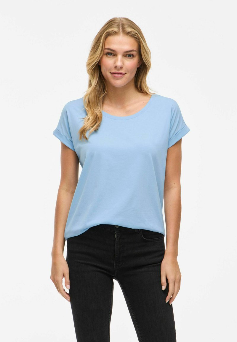 T-shirt azzurro a maniche corte in morbido cotone, con scollatura rotonda, vestibilità rilassata, maniche arrotolate e abbinato a jeans neri.