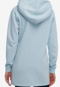 Sudadera con capucha de color azul claro, con una textura suave, mangas largas y un corte ligeramente alargado. Presenta una capucha redondeada en la parte posterior.