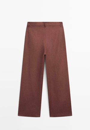 Braune weit geschnittene Hose mit Gürtelschlaufen und ohne sichtbare Taschen, vor weißem Hintergrund aufgehängt dargestellt.