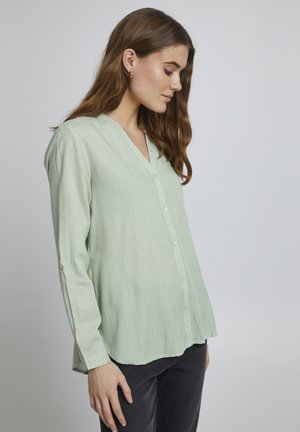 Camisa de manga larga de color verde claro, con rayas verticales, escote en V y cierre de botones. Tejido suave con un corte relajado y dobladillo redondeado.