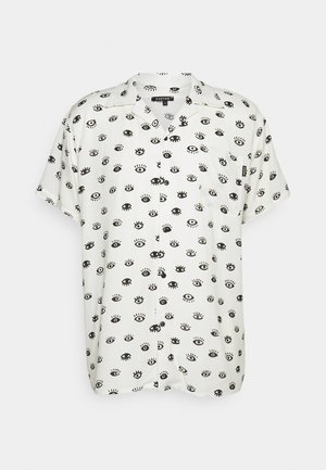 Chemise à manches courtes en tissu léger, avec un fond blanc orné d'un motif d'œil noir répété et une poche poitrine.