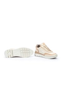 Zapatillas beige hechas de cuero y material sintético, con una suela texturizada, diseño con cordones y un collar acolchado para mayor comodidad.