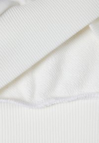 Tela blanca con capas de materiales acanalados y texturizados; presenta superficies suaves y delicadas con un brillo sutil.