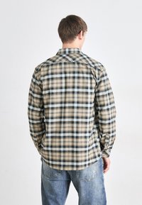 Beige plaid shirt featuring blue and black check patterns, long sleeves, and a button-down collar. Made of soft fabric with a slightly textured finish.