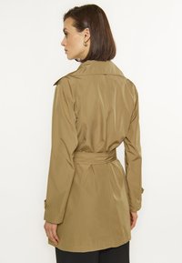 Khaki płaszcz trench z paskiem w talii, długimi rękawami i klasycznym kołnierzem. Gładka, lekka tkanina o dopasowanym kroju i detalach w postaci pliski z tyłu.