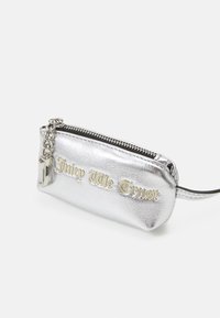 Stříbrná metalická mini taška s embosovaným textem "Juicy Me Trust" na zlaté barvě. Obsahuje zipové uzavření a řetěz na připevnění. Měkká textura.