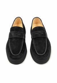 Zwarte suède loafers met een afgeronde vorm, een gestikte accenten op het bovenwerk en rubberen zolen voor grip. De binnenkant heeft een beige voering.