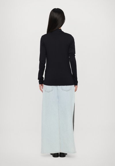 Black long-sleeve top paired with a light blue maxi skirt, featuring a slit, frayed hem, and two back pockets. Smooth texture and casual silhouette.
