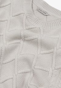 Suéter de punto gris claro con un patrón texturizado de diamantes, cuello acanalado y etiqueta que dice "DAN JOHN". Material suave con costuras visibles.