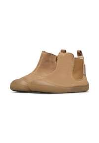 Stivaletti in suede beige per bambini con suole in gomma, pannelli laterali elastici e linguette per il sollevamento su sfondo bianco.