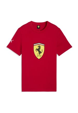 Maglietta rossa a maniche corte con scudetto Ferrari giallo e stemma nero del cavallino rampante al centro del petto e logo Puma bianco sulla manica destra.