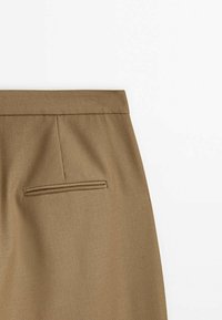 Vue arrière d’un pantalon marron montrant la ceinture, une poche passepoilée simple et une couture centrale au dos sur tissu lisse.