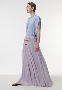 Lichtblauw top met gedrapeerd ontwerp, gecombineerd met een vloeiende, lavendelkleurige maxi-rok met geborduurde accenten en een gerimpelde tailleband.